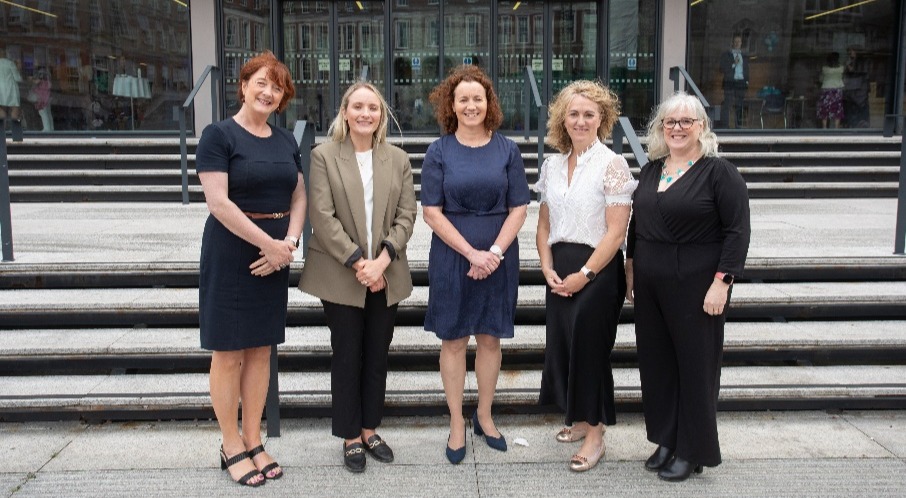 A group of women standing in front of stairsDescription automatically generated