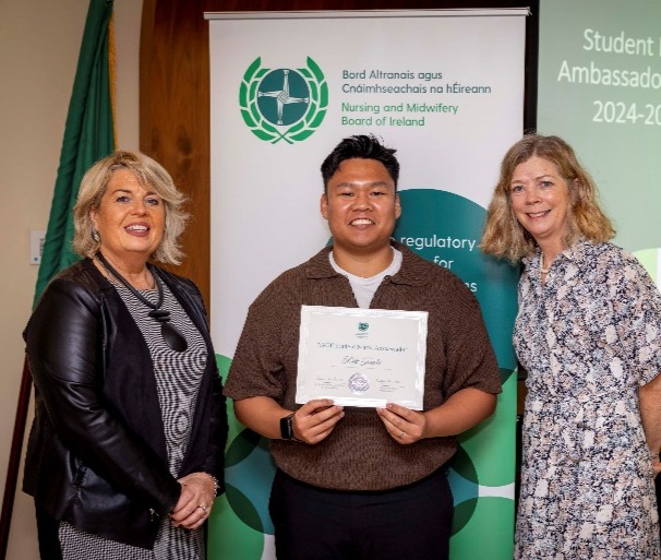 A group of people standing in front of a bannerDescription automatically generated